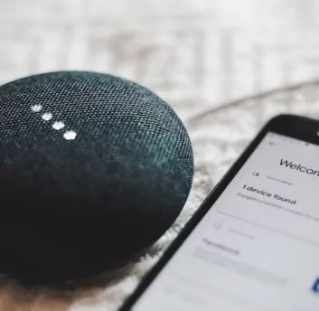 An IoT-enabled speaker alongside mobile phone.